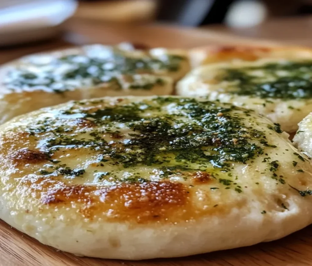 Golden-brown herb focaccia topped with fresh rosemary, thyme, and coarse sea salt, fresh out of the oven on a rustic baking tray.